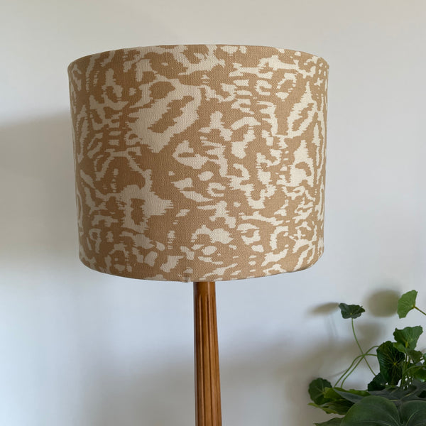 Lamp with a patterned beige shade on a white background