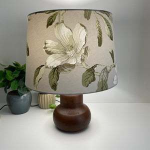 Large 'tapered 46' lampshade with white magnolia fabric, lit on brown base, designer light shade handcrafted by shades at grays, long view.