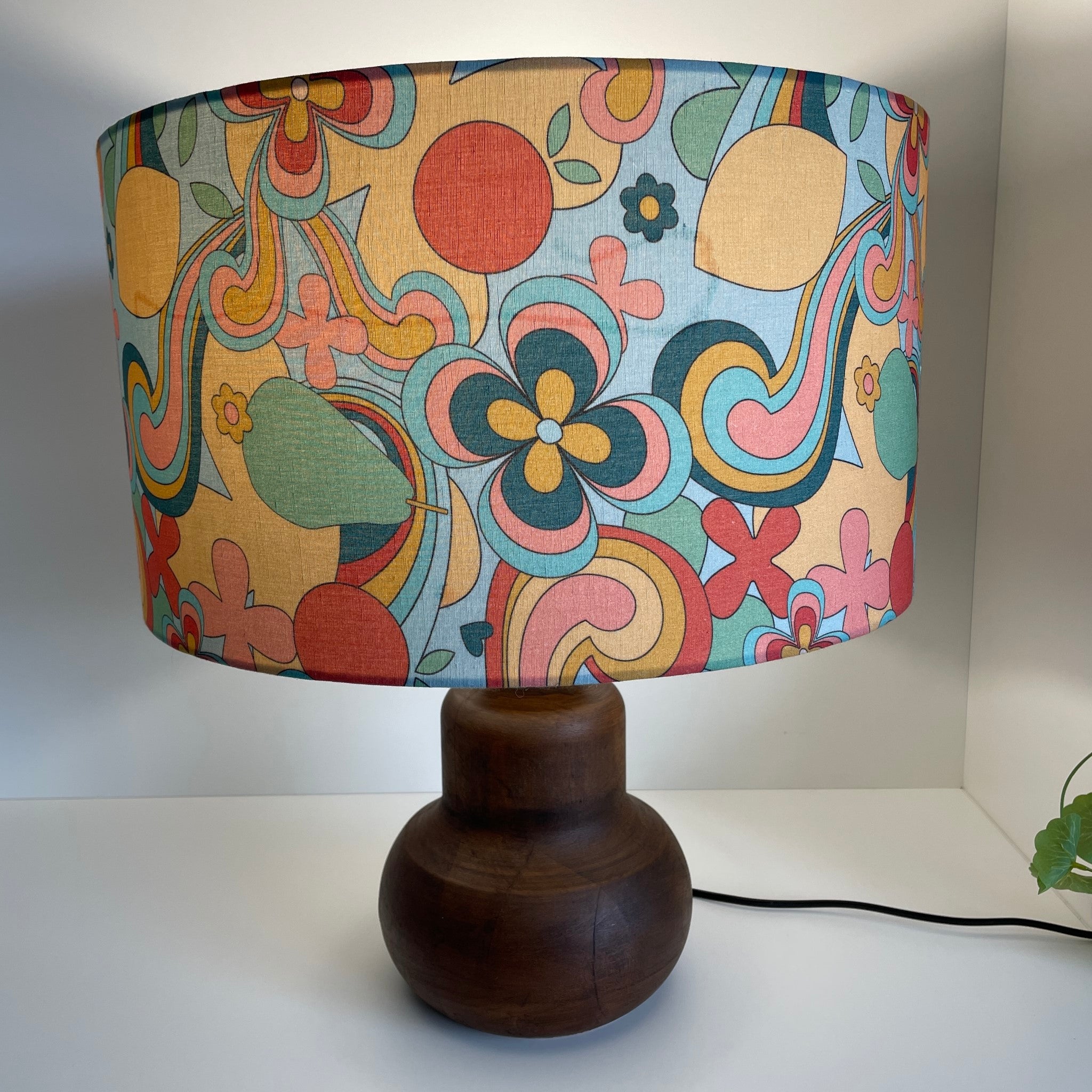 Large barrel with 60s swirl fabric on brown base, lit, showing watermark on fabric, by shades at grays.