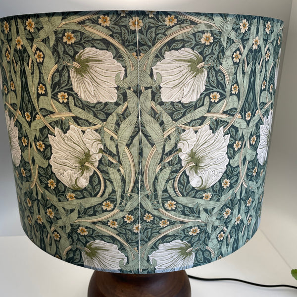 Large drum in Morris pimpernel olive fabric on brown base, lit, close up of 2nd seam, by shades at grays.