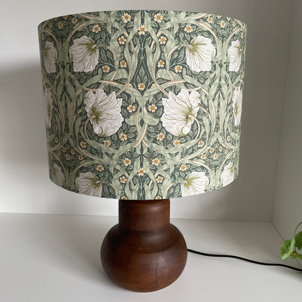 Large drum in Morris pimpernel olive fabric on brown base, unlit by shades at grays.