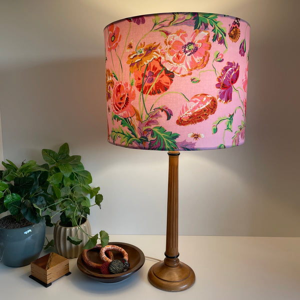Drum light shade with Kaffe Fassett meadow pastel fabric, lit, on wooden lamp base, by shades at grays, nz.