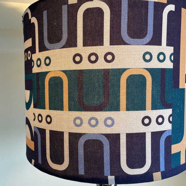 Large drum style lampshade with geometric harmony blue fabric, lit, close up.