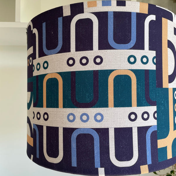 Large drum style lampshade with geometric harmony blue fabric, unlit, close up.