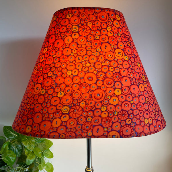 Large lamp shade handcrafted by shades at grays in nz with Kaffe Fassett button mosaic ornage fabric, lit.