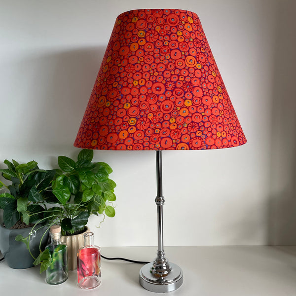Large lamp shade handcrafted by shades at grays in nz with Kaffe Fassett button mosaic ornage fabric, unlit on silver base.