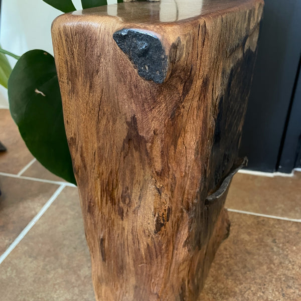 Large railway anchor on top of polished top of wharf timber door stop, left edge erosion lines and tar mark, crafted by shades at grays.