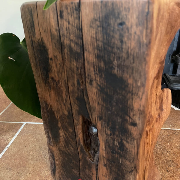 Large railway anchor on top of polished top of wharf timber door stop and back side with striations and tar marks, close up crafted by shades at grays.