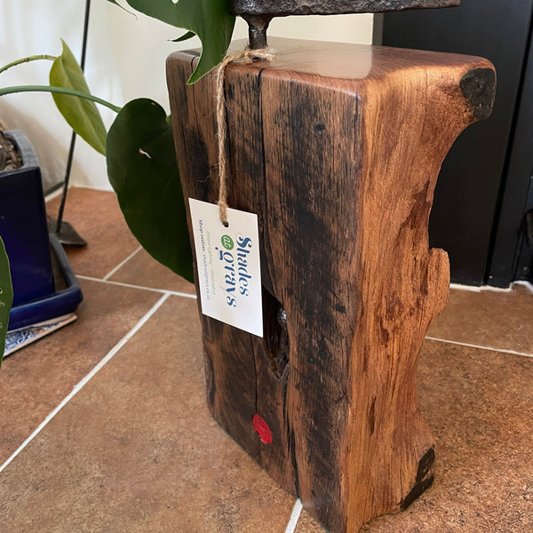 Large railway anchor on top of polished top of wharf timber door stop and back side with striations and tar marks, crafted by shades at grays.