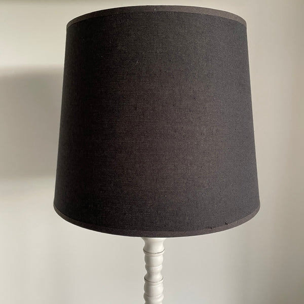 Large black tapered lampshade on white base, secondhand, close up.