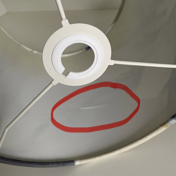 Close-up of a white lampshade with a red circle highlighting a small defect.