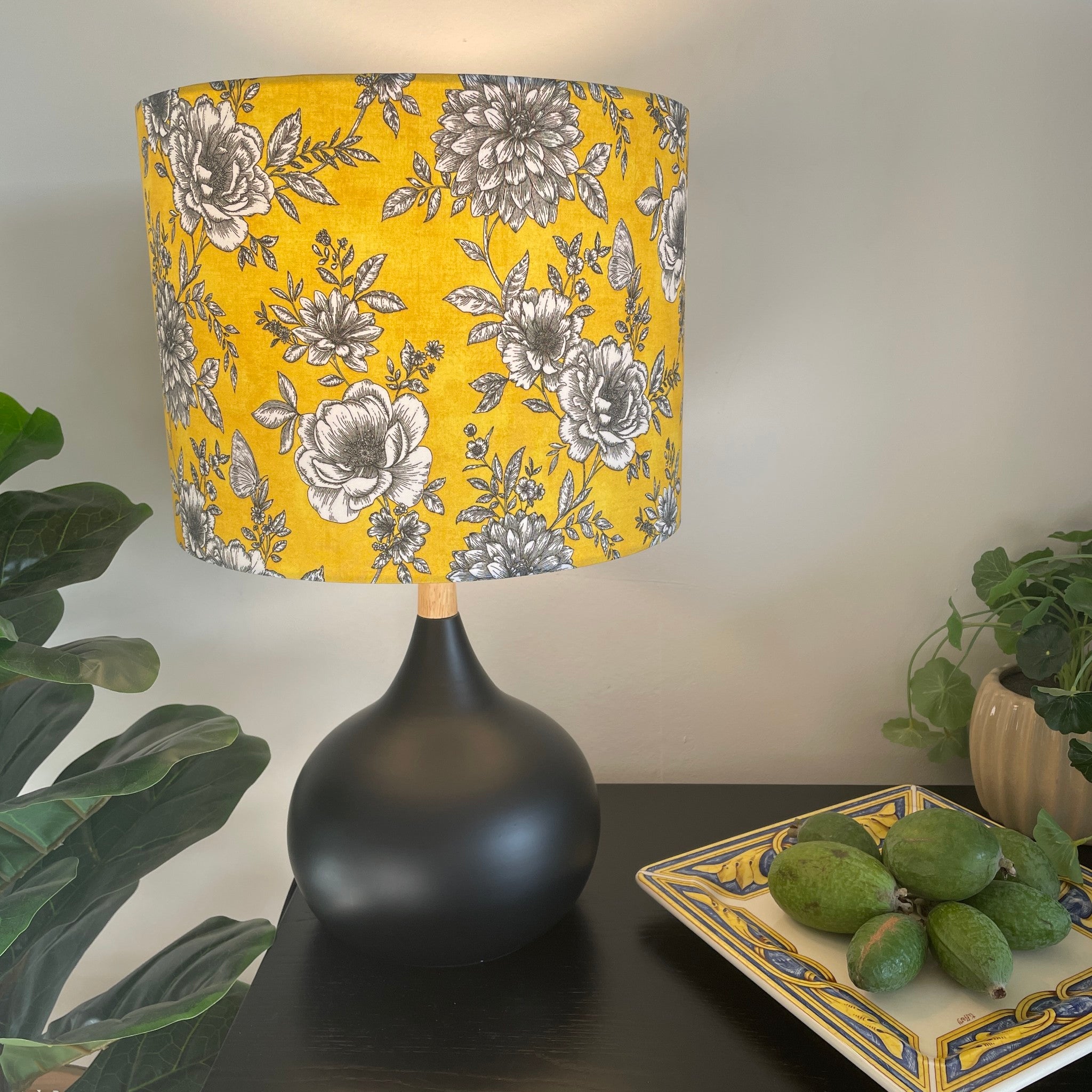 Medium drum handcrafted by shades at grays with floral glow fabric, lit on black base.