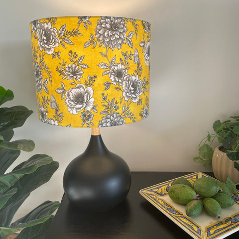 Medium drum handcrafted by shades at grays with floral glow fabric, lit on black base.