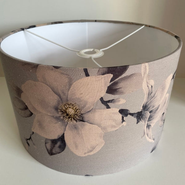 Medium barrel lampshade with large magnolia flowers on a grey background, ceiling pendant.