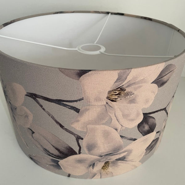 Medium barrel lampshade with large magnolia flowers on a grey background, ceiling pendant, side view.