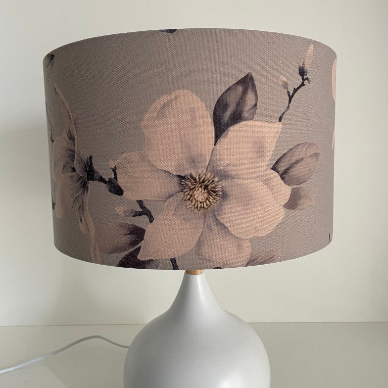 Medium barrel lampshade with large magnolia flowers on a grey background, table lamp,unlit.