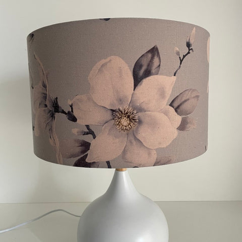 Medium barrel lampshade with large magnolia flowers on a grey background, table lamp,unlit.