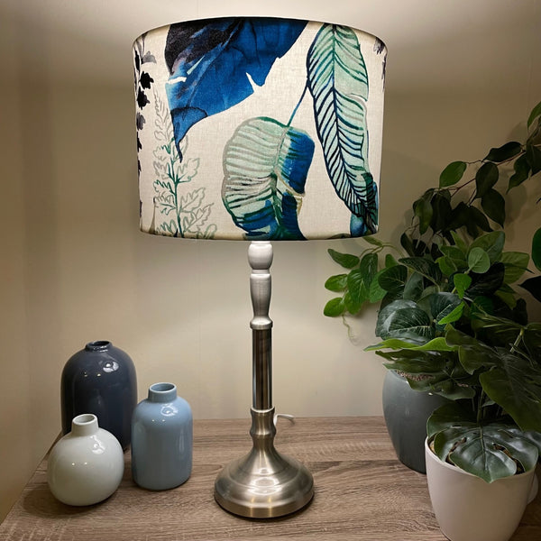 Medium drum handcrafted fabric lamp shade with watermark palm fabric, lit on brushed chrome stand..