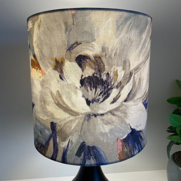 Medium cylinder lampshade with two tone roses blue fabric, lit.