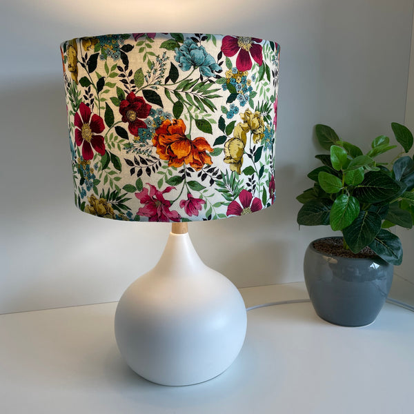Medium drum bespoke lampshade with flower garden fabric, lit on white base, by shades at grays nz