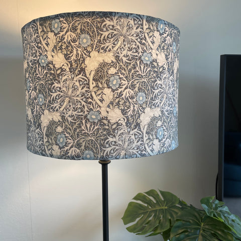 Medium drum style lampshade with Morris Pure Seaweed fabric on black base, lit by shades at grays, nz.