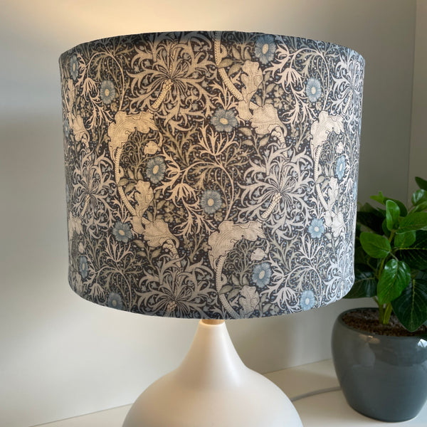 Medium drum style lampshade with Morris Pure Seaweed fabric on white base, lit by shades at grays, nz.