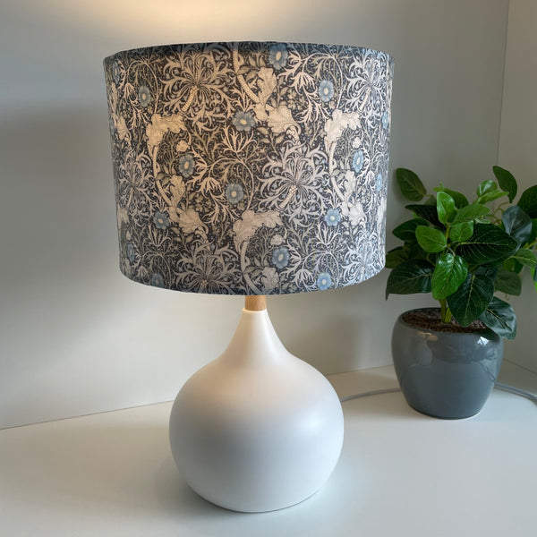 Medium drum style lampshade with Morris Pure Seaweed fabric on touch white base, lit by shades at grays, nz.