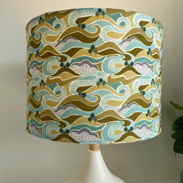 Medium drum style lampshade with hills and trees fabric, lit by shades at grays nz