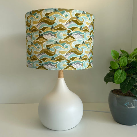 Medium drum style lampshade with hills and trees fabric on white base, lit by shades at grays nz