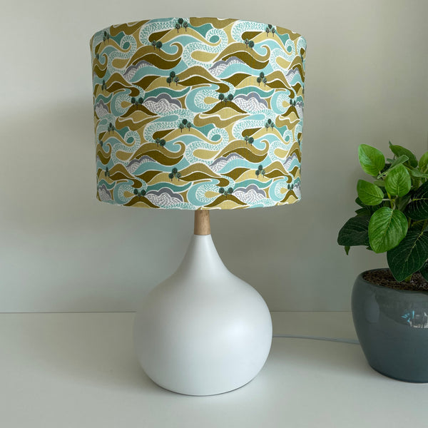 Medium drum style lampshade with hills and trees fabric on white base, unlit by shades at grays nz