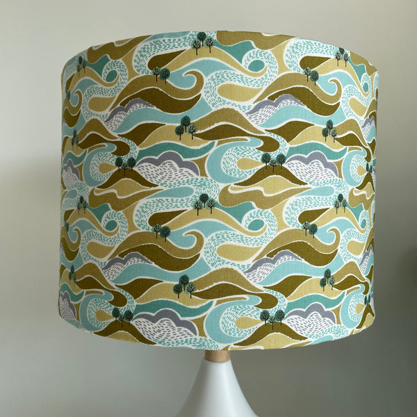 Medium drum style lampshade with hills and trees fabric, unlit, lit by shades at grays nz
