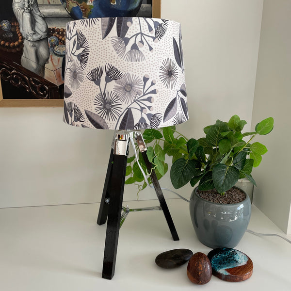 Medium tapered eucalyptus blossom lampshade on black tripod, unlit.