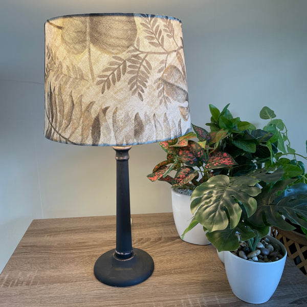 Medium tapered fabric lamp shade, lit on black stand