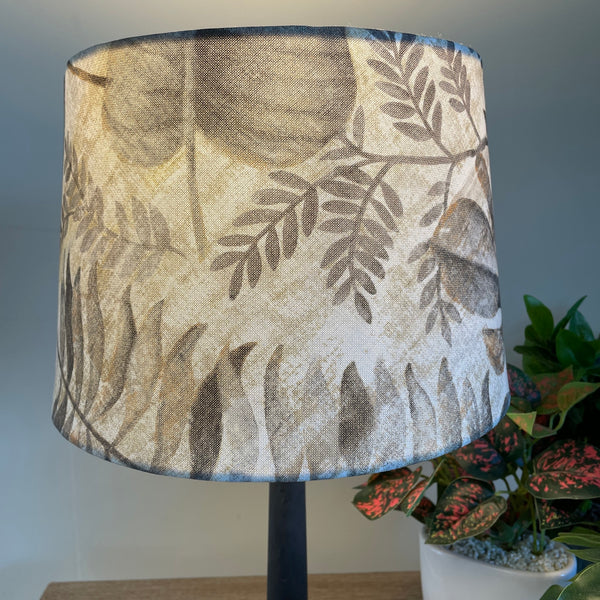 Medium tapered fabric lamp shade, lit.