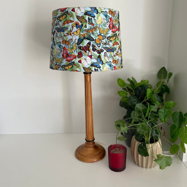 Medium tapered handcrafted fabric lampshade, unlit on wooden base.