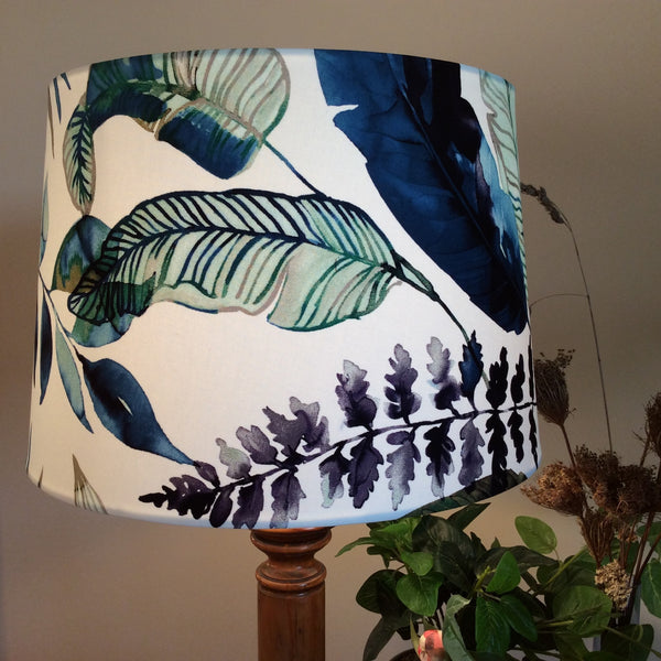 Large tapered handcrafted fabric lamp shade with watermark palm fabric, lit.
