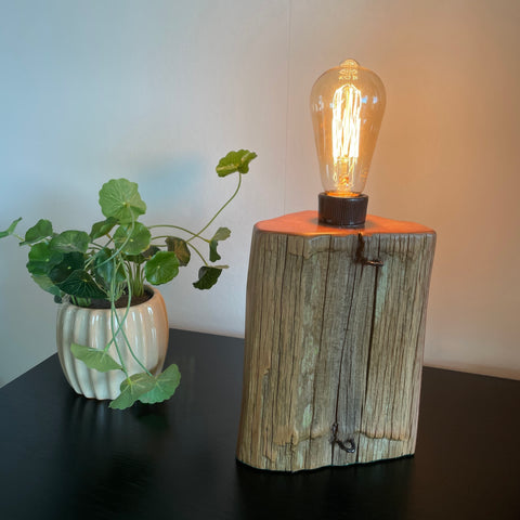 Original totara wood fence post table lamp, crafted by shades at grays, lit.