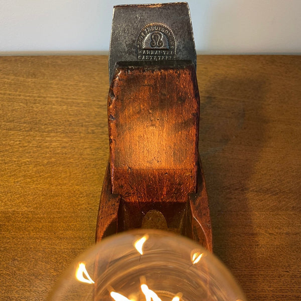 Wood table lamp crafted from authentic carpenters plane, with replica edison bulb, lit, close up of orignal brand on cutting blade, sold by shades at grays.