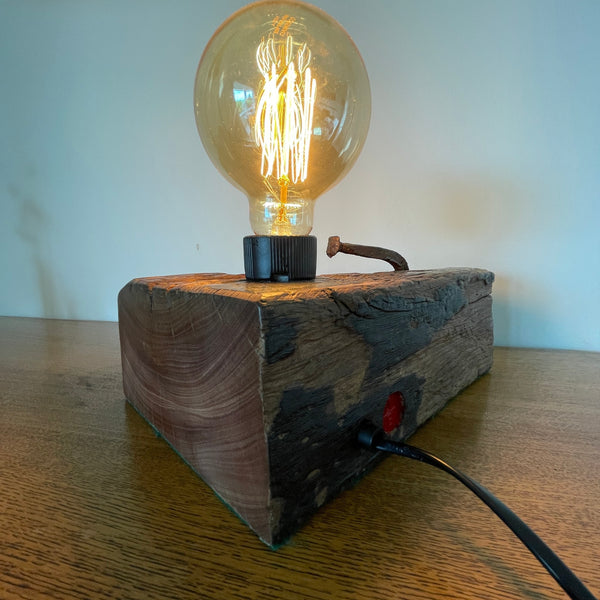 Original wharf timber table lamp handcrafted by shades at grays with edison bulb, lit, back view.