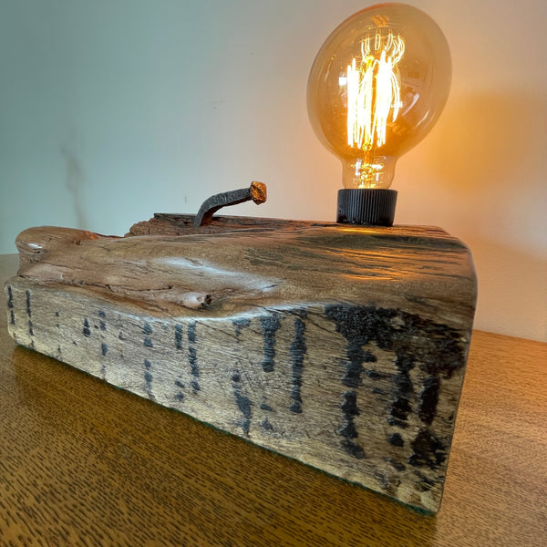 Original wharf timber table lamp handcrafted by shades at grays with edison bulb, lit, close up of front view with tar  marks