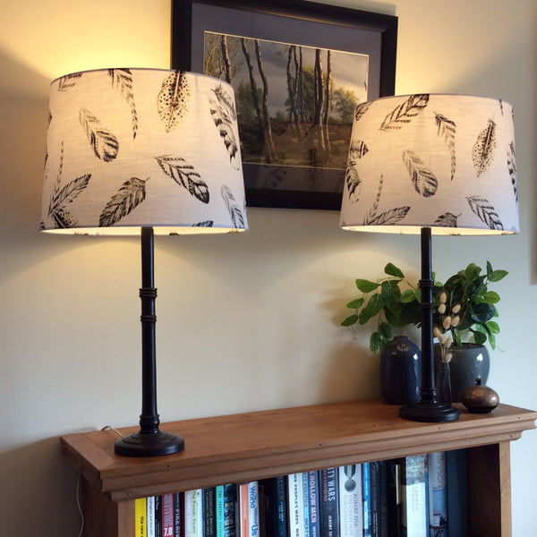 Pair of table lamps with bespoke light shades, lit.