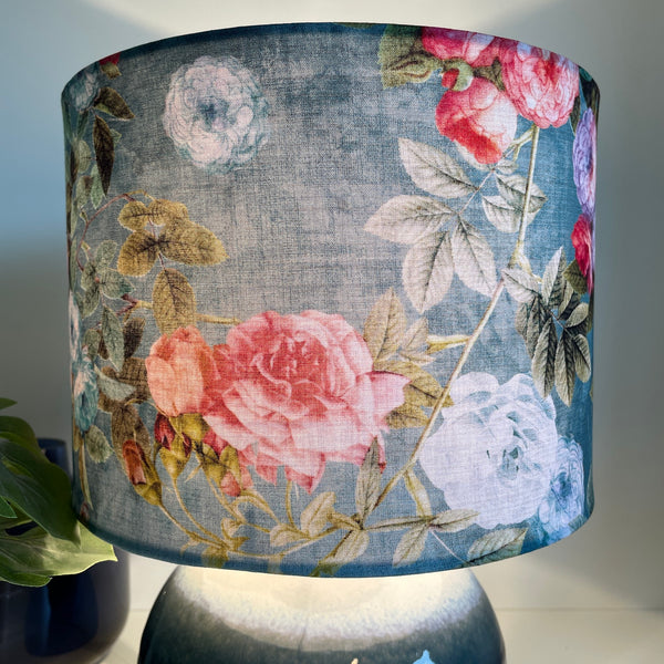 Ocean blue floral bespoke fabric lamp shade, on blue and white ceramic base, lit.