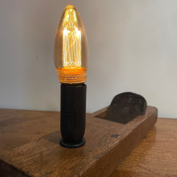 Rare table lamp upcycled from Japanese carpenter's plane with E14 candle bulb, lit, back view.