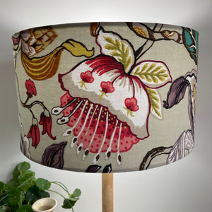 Ready made medium barrel table lampshade with magenta floral fabric, lit.