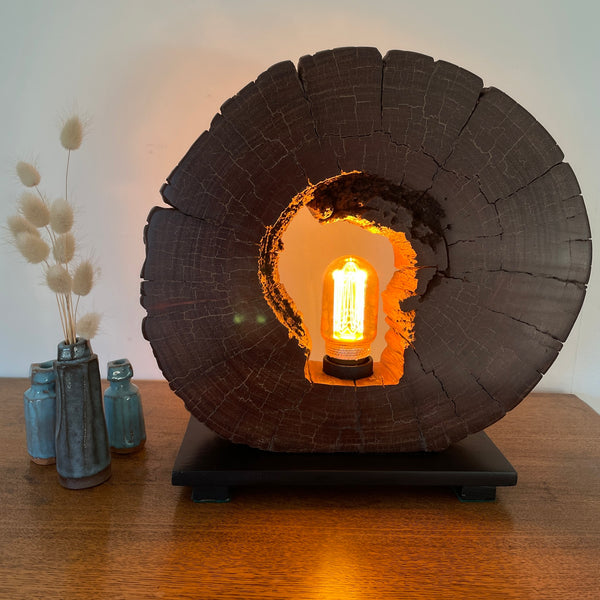 Reclaimed heritage lamp handcrafted from eroded jarrah telegraph pole, lit, front view.
