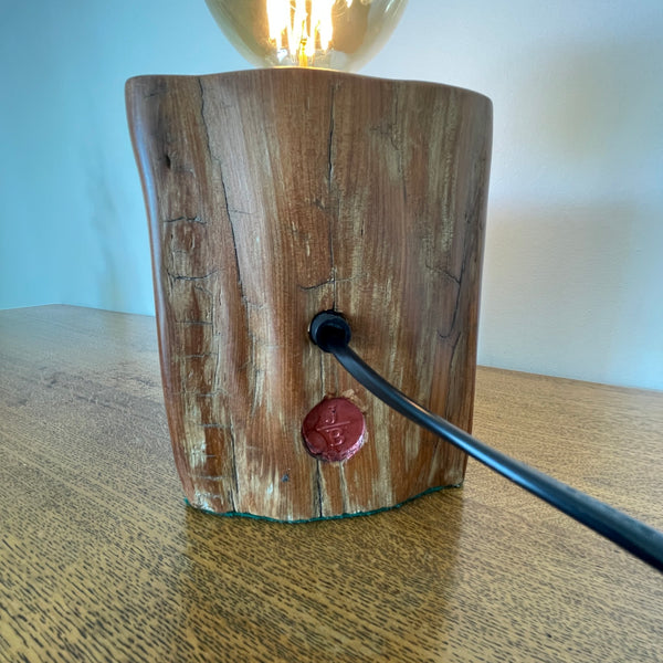 Reclaimed tōtara fence post wood table lamp, crafted by shades at grays, smooth back view with black lead.