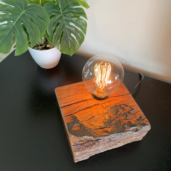 Unique wood table lamp crafted by shades at grays from 100 year old reclaimed wharf timber, lit, view of origianl markings and wood grain.