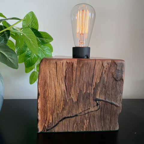 Reclaimed wood table lamp with distinctive wave shaped erosion mark and edison bulb, lit, created by Shades at Grays