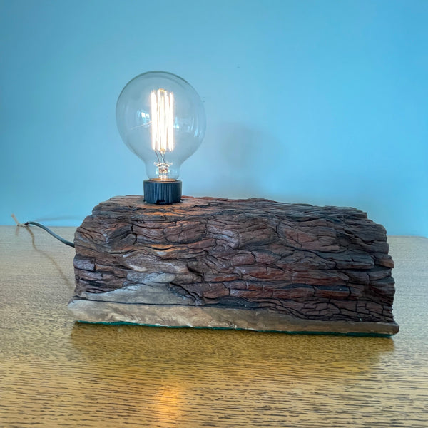 Upcycled wood table lamp, wavy patterned erosion grooves, and additional edison bulb, lit by Shades at Grays long view of front.