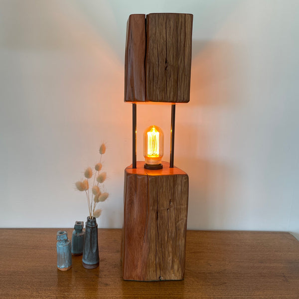 Reclaimed wood table lamp crafted by shades at grays with a split totara post and LED bulb, long front view.